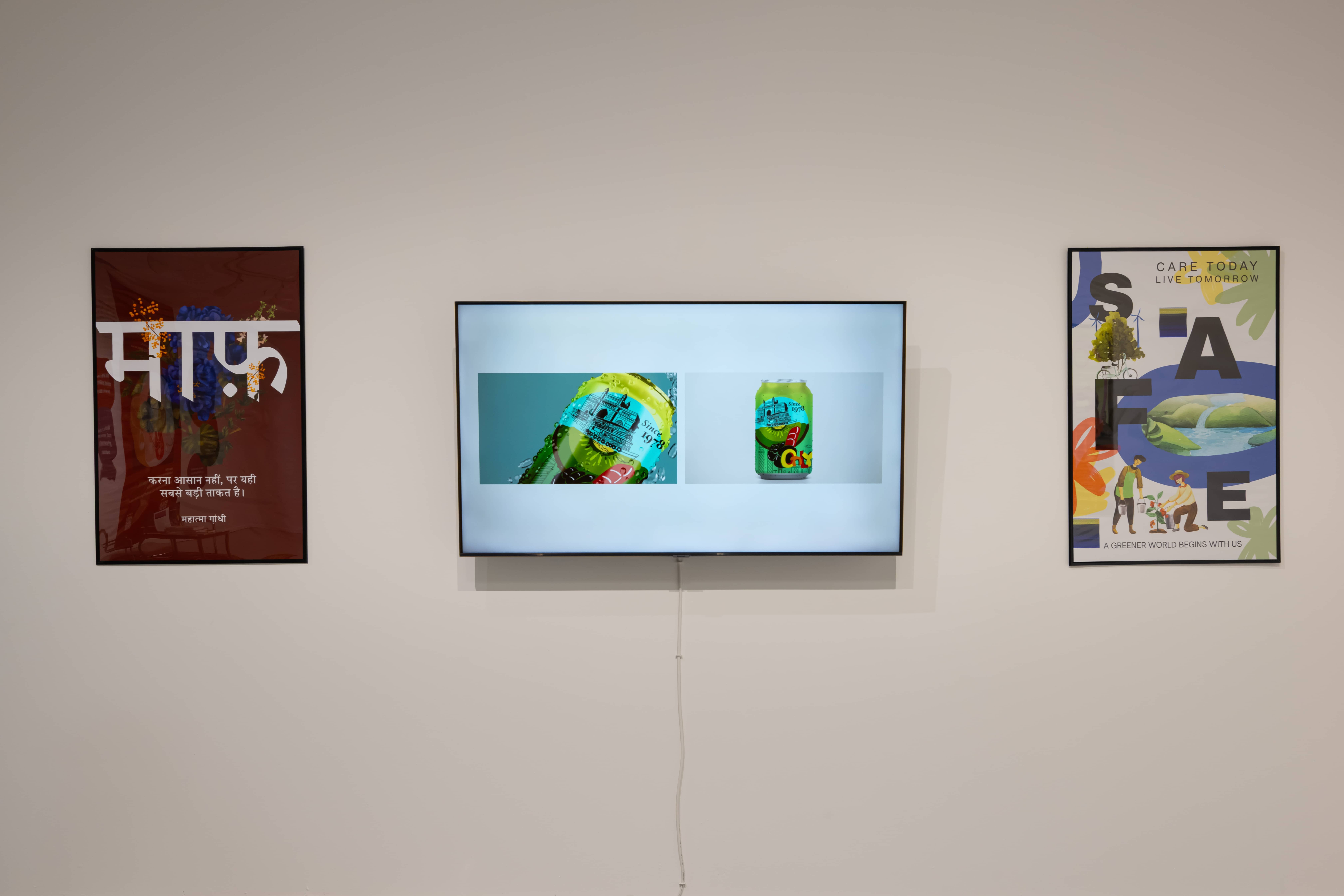 A wall display featuring a central television screen showing images of a fruit soda can, flanked by two posters with text and illustrated designs.