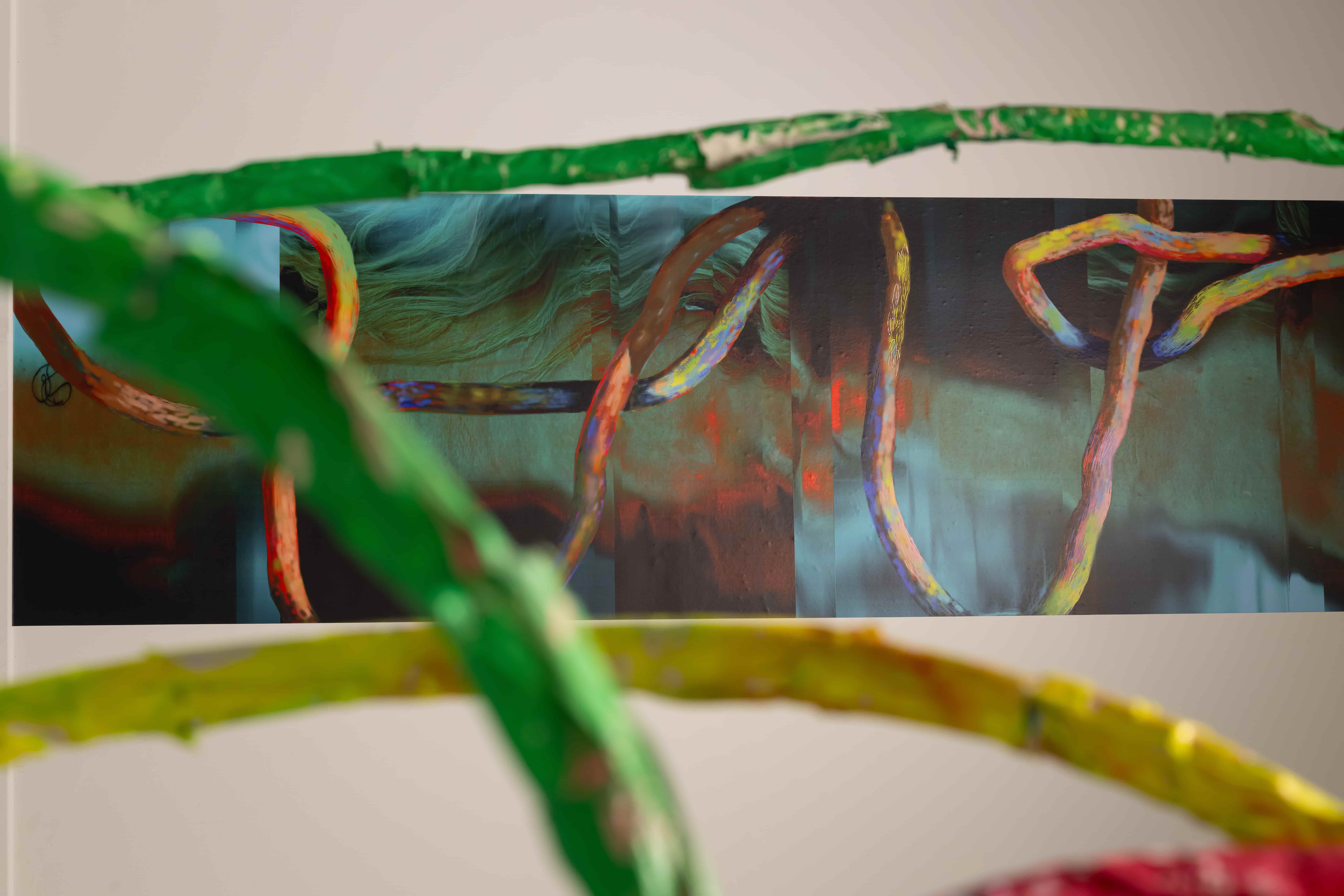 A tall abstract painting of multicolored, vine-like lines winding across a dark teal and rust background, framed by bright green and yellow branches; vivid, dreamlike mood.